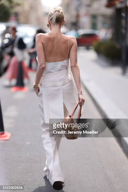 Leonie Hanne is seen wearing a complete Fendi outfit consisting of golden sunglasses with brown lenses, a white lacy top, white suit pants with a...