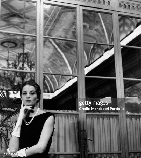 French actress and model Capucine posing in a hotel wearing a Givenchy dress. Rome, 1962