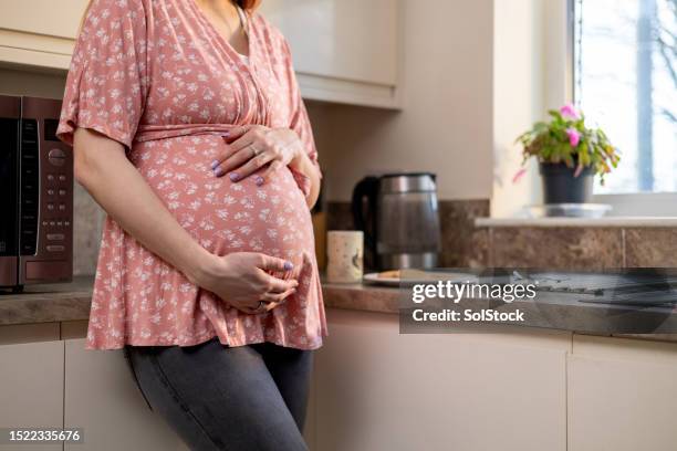 pregnant woman touching stomach - maternity wear stock pictures, royalty-free photos & images