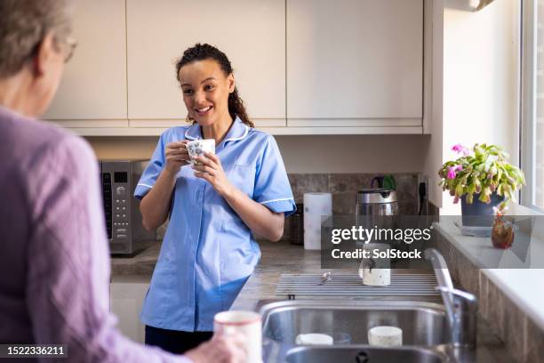 young female home nurse talking with patient - serviços essenciais imagens e fotografias de stock