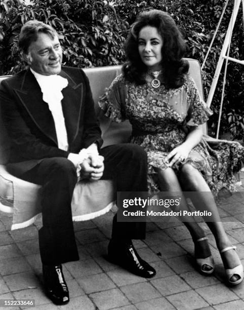 British-born American actress Liz Taylor and her husband, the British actor Richard Burton sitting on a swing seat. Taormina, 1970s