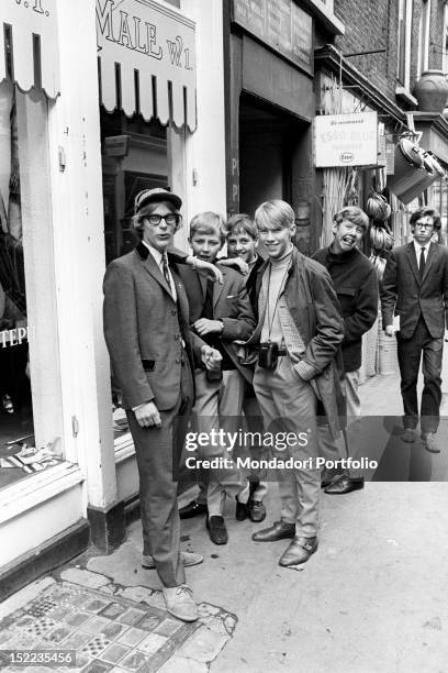 Group of British young mods posing outside John Stephen's clothes shop. One of them wears a jacket in the Edwardian style and a hat in the Sherlock...