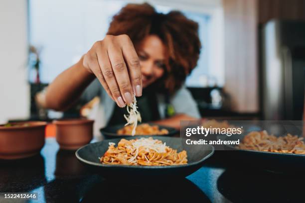 frau, die geriebenen käse auf makkaroni legt - parmesan stock-fotos und bilder