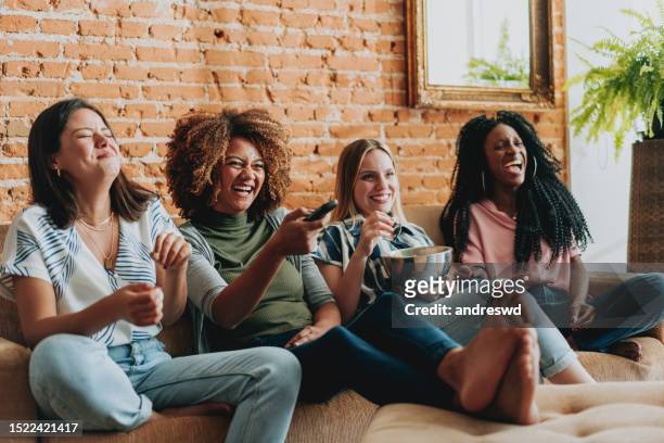 group of female friends watching tv at home - watching tv stock pictures, royalty-free photos & images