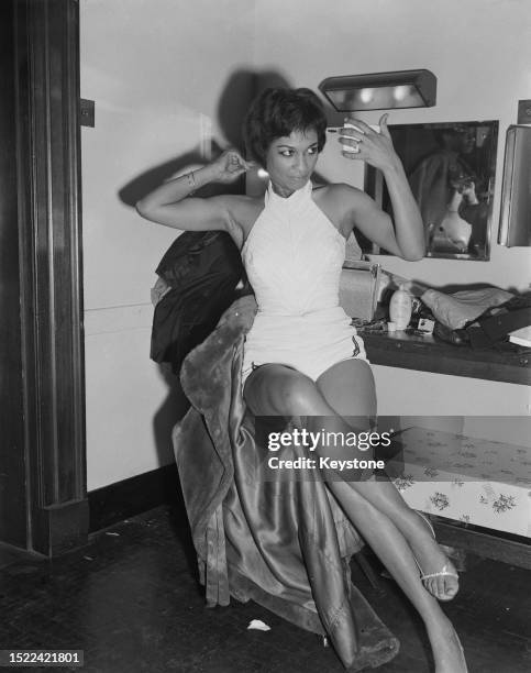 Caribbean Carnival Queen winner Faye Sparks looks in a handheld mirror while combing her hair in a dressing room at St Pancras Town Hall, London,...