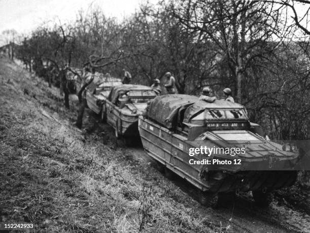 American amphibious trucks 'DUCKS' wait in a sheltered lane for the signal to ferry US soldiers across the Saar river into Germany .