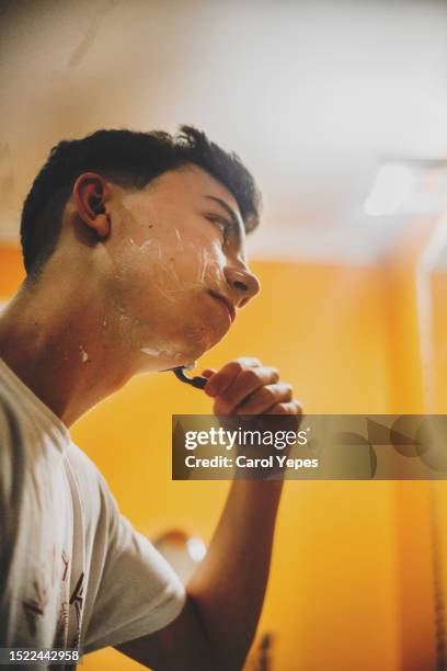 young male  using a manual razor - male hair removal stock-fotos und bilder