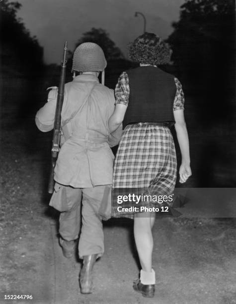 Liberator and liberated woman walk arm to arm down a road in the town of Graves September 17, 1944 .