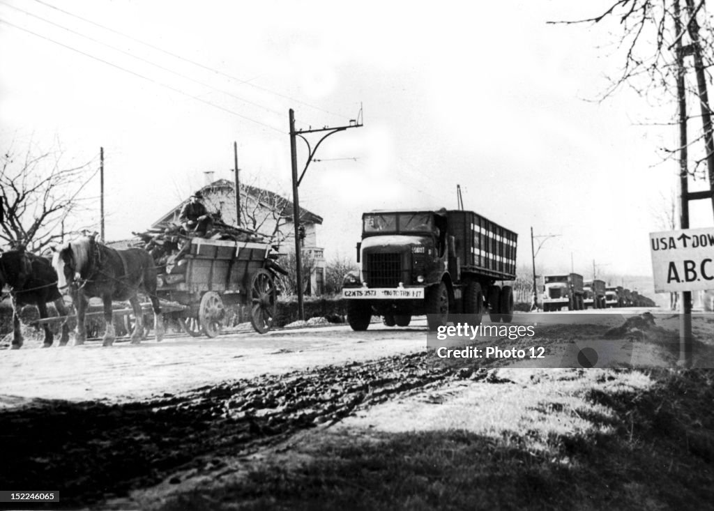A farm wagon pulls to side of the road to make room for a convoy of high-powered US, trucks speeding war cargo from the Belgian port of Antwerp to an inland marshalling yard