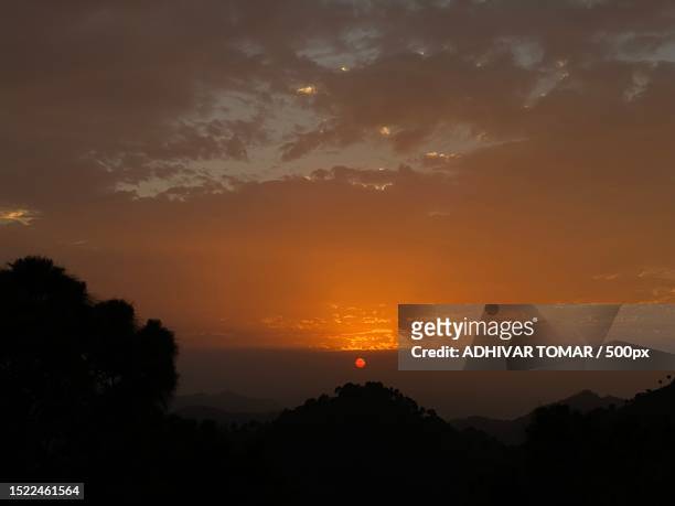 scenic view of silhouette of mountains against sky at sunset - tomar el sol stock-fotos und bilder