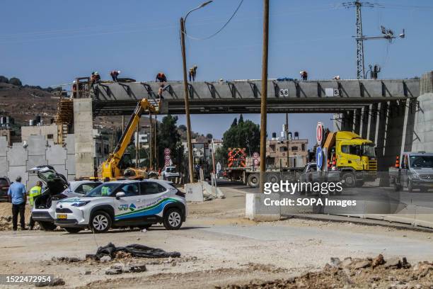 Palestinian and Israeli workers install a bridge in the town of Hawara, south of Nablus. The bridge is being built for the benefit of residents of...