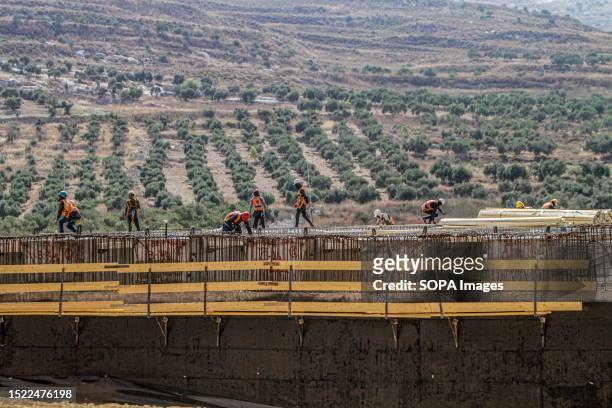 Palestinian and Israeli workers install a suspension bridge in the town of Hawara, south of Nablus. The bridge is being built for the benefit of...