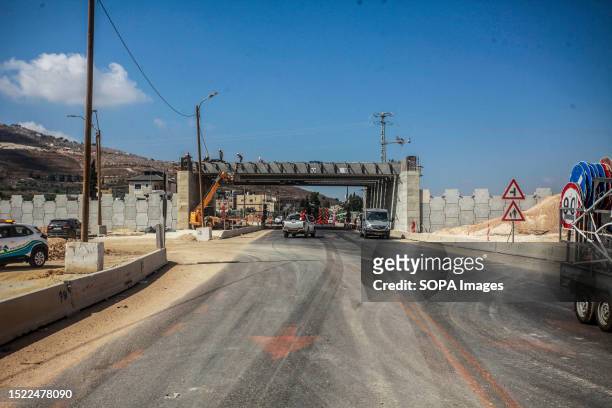 An Israeli soldier guards the Palestinian and Israeli workers installing a bridge in the town of Hawara, south of Nablus, to improve the ease,...