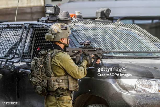 An Israeli soldier guards the Palestinian and Israeli workers installing a bridge in the town of Hawara, south of Nablus and for the benefit of...