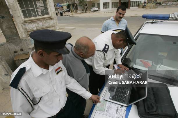 Iraqi police officers use a laptop to fine drivers caught driving without seatbelts in Baghdad on April 19, 2008. Iraqi police is cracking down on...