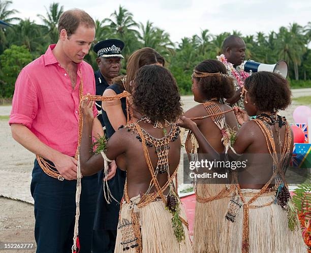 Young girls present Prince William, Duke of Cambridge with a garland as they arrived in Honiara on their way to Tivanipupu on day 7 of their Diamond...