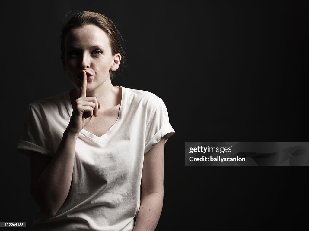 Young Woman Holding Finger To Her Lips.