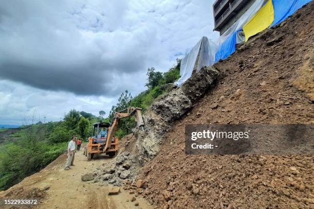 An excavator is being used at the site of a landslide along a road on the outskirts of the northern Indian hilltown of Shimla on July 11, 2023. Days...