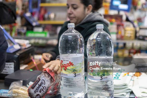 Cashier charges water bottles in a supermarkets as tap water contains high salinity and chemicals on July 06, 2023 in Montevideo, Uruguay. The...
