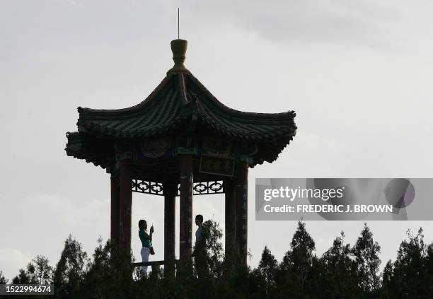 Woman photographs her friend with a mobile phone from a pavilion in a new park at the Dajingmen Great Wall, 24 May 2006, overlooking the historic...