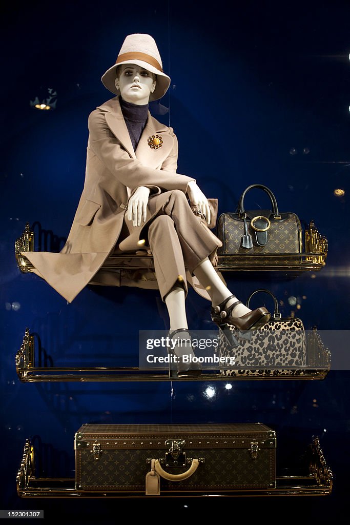 A mannequin sits amongst bags and luggage in a Louis Vuitton store