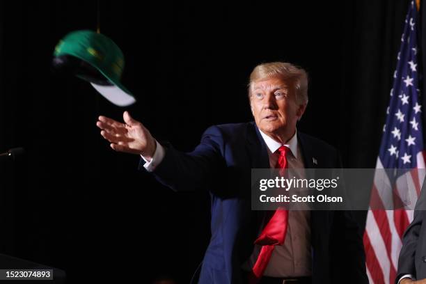 Former U.S. President Donald Trump tosses hats to supporters as he arrives for a Farmers for Trump campaign event at the MidAmerica Center on July...