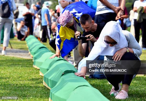 Bosnian Muslim woman, survivor of the Srebrenica 1995 massacre mourns near the casket containing the remains of a relative and victim of the...
