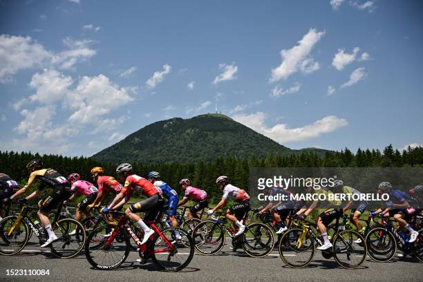 Jumbo-Visma's Danish rider Jonas Vingegaard wearing the overall leader's yellow jersey cycles with the pack of riders past the Puy de Dome during the...