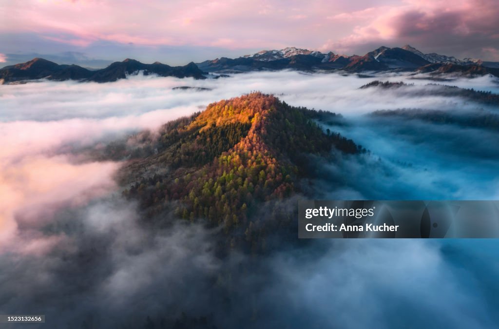 Aerial view of Mountain peak with sunlight in fog at sunset