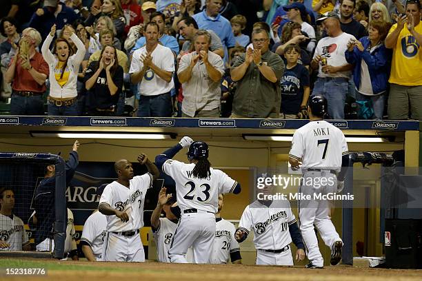 Rickie Weeks of the Milwaukee Brewers celebrates in the dugout with Nyjer Morgan and Ron Roenicke after hitting a two-run home run in the bottom of...