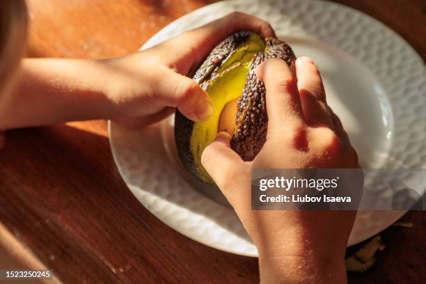 human hands opening avocado. healthy meal - rijp stockfoto's en -beelden