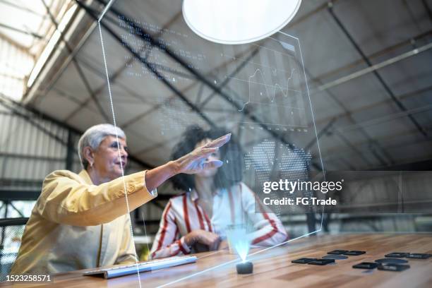 collègues utilisant un appareil de réalité augmentée lors d’une réunion au bureau - hologramme photos et images de collection