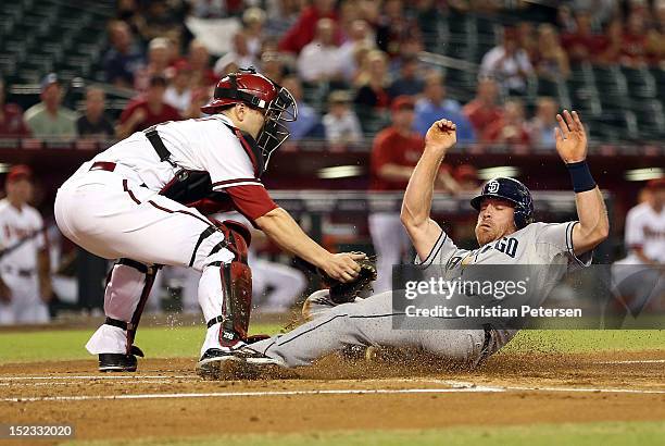 Logan Forsythe of the San Diego Padres slides in to socre a run pas the tag from catcher Miguel Montero of the Arizona Diamondbacks during the first...