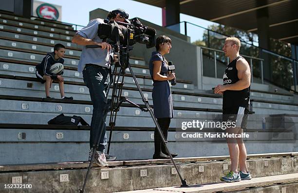 Michael Crocker speaks to the media as a young fan watches during a South Sydney Rabbitohs NRL media session at Redfern Oval on September 19, 2012 in...