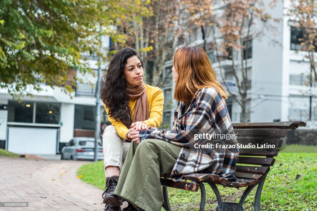 Young woman consoling her friend on the public park