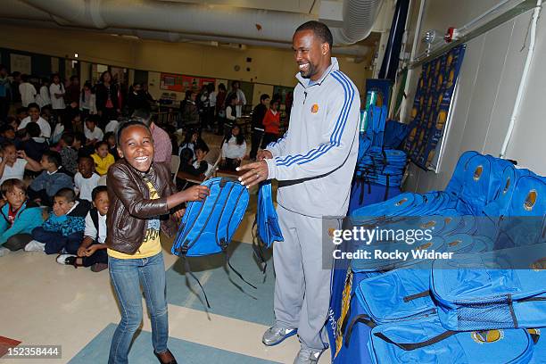 Golden State Warriors Assistant Coach Kris Weems distributes backpacks to students at Garfield Elementary on September 17, 2012 in Oakland,...