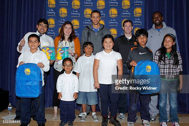 Golden State Warriors guard Stephen Curry and Assistant Coaches Darren Erman and Kris Weems pose with students and staff members at Garfield...