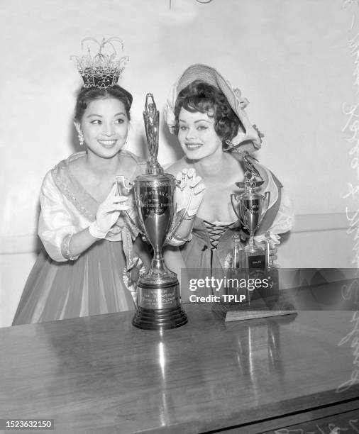 Miss Universe contestants Hyum Choo Oh of Korea and Pamela Anne Searle of England pose in front the Long Beach trophies for most popular and most...