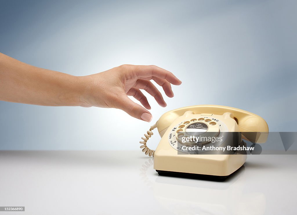 Woman's hand reaching for a retro telephone