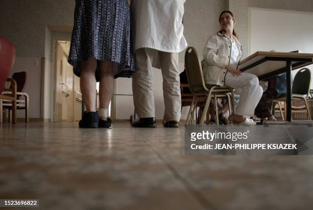Une personne atteinte de la maladie d'Alzheimer aidée par un infirmier passe à côté d'une infirmière dans une salle de détente, le 22 décembre 2006...