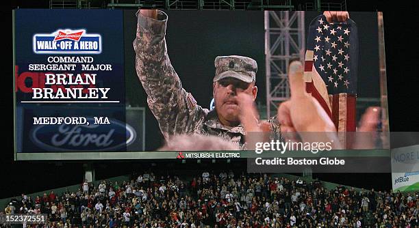 Command Sergeant Major Brian Branley, of Medford, can be seen on the centerfield scoreboard as he acknowledges the cheers of the crowd as he carries...