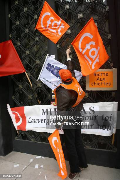 Une personne accroche des drapeau de la CFDT sur la porte du siège du groupe Areva, lors d'une manifestation de salariés d'Areva NC, branche...
