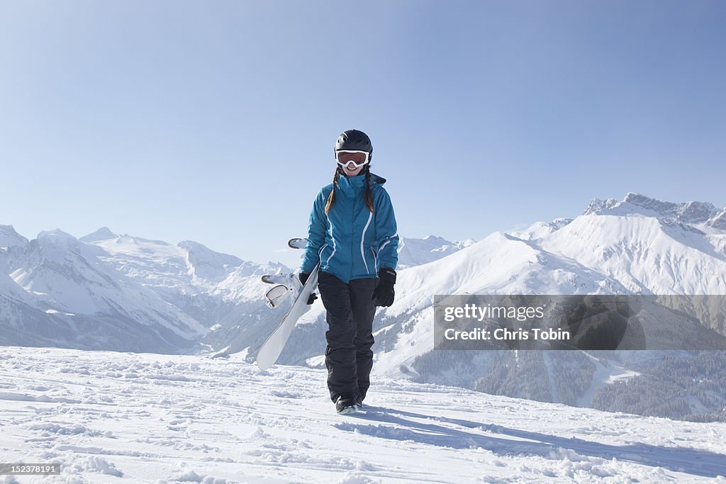 Young woman walking with snowboard