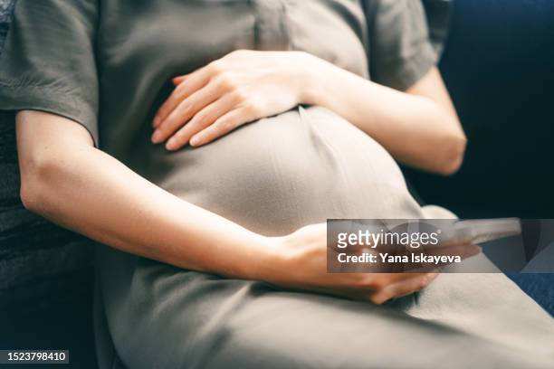 an unrecognizable pregnant woman using mobile phone pregnancy tracking app - morning sickness fotografías e imágenes de stock