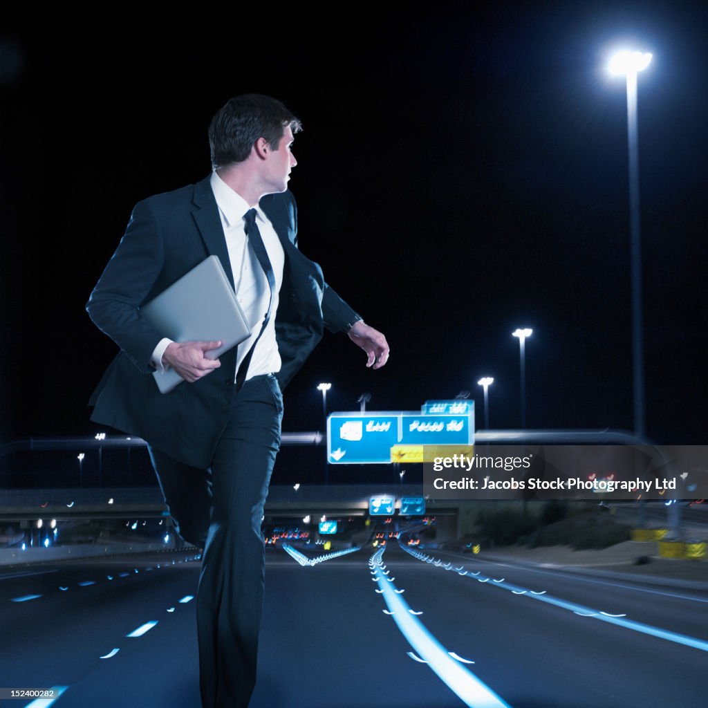 Caucasian businessman running on urban freeway at night