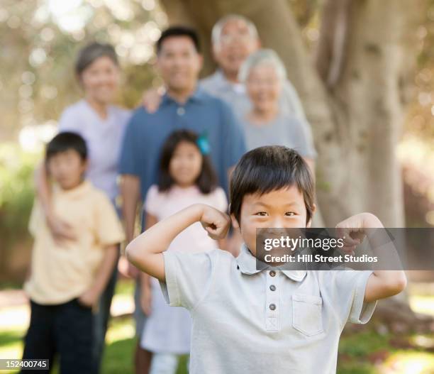 asian boy flexing his muscles as family watches - group of people flexing biceps stock pictures, royalty-free photos & images