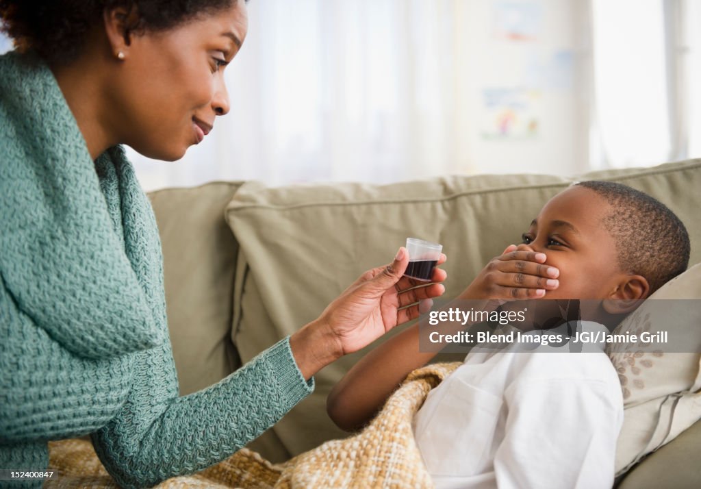 Black mother giving son cough syrup
