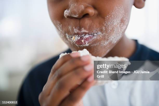 messy black boy eating donut - eating donuts stockfoto's en -beelden