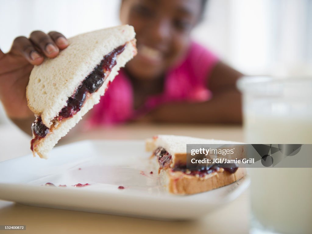 Black girl eating peanut butter and jelly sandwich