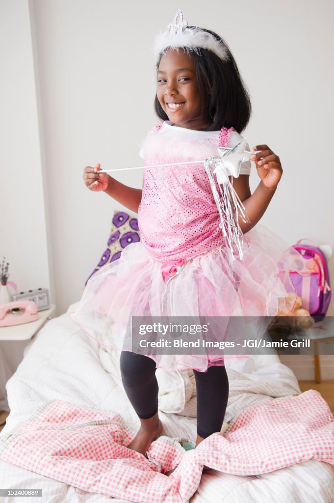 Black girl in fairy costume standing on bed